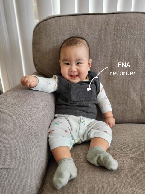 A happy baby wearing a vest with a small child-friendly recorder